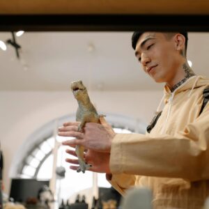 A young man examines a toy iguana inside a trendy fashion and retail store.